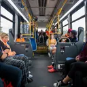 Students seated aboard a Get on the Bus transit tour bus, mid-conversation with the program's director.