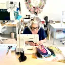 Wild Bobbin's Kingston studio, a sewing instructor working at a machine surrounded by workshop tables and supplies.