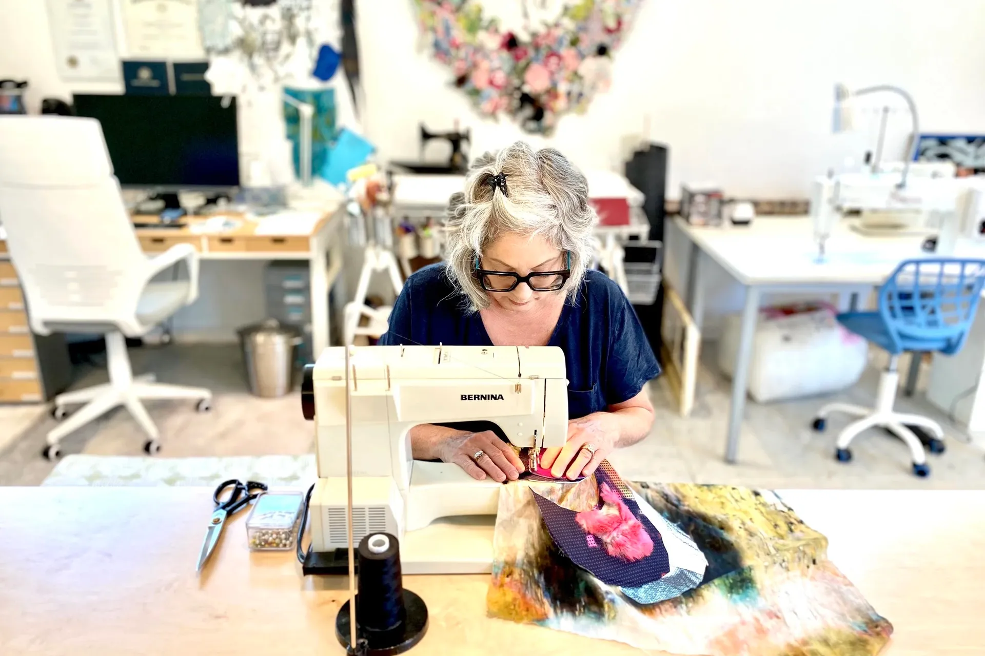 Wild Bobbin's Kingston studio, a sewing instructor working at a machine surrounded by workshop tables and supplies.